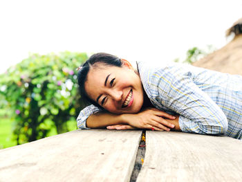 Portrait of smiling young woman lying on wood