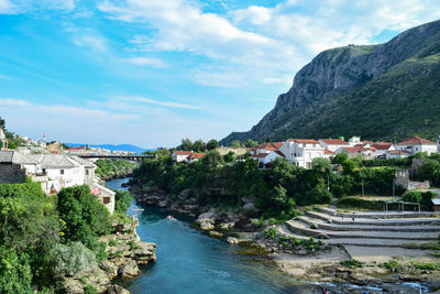 River amidst buildings and mountains against sky