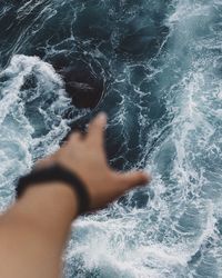 Cropped image of person hand against sea