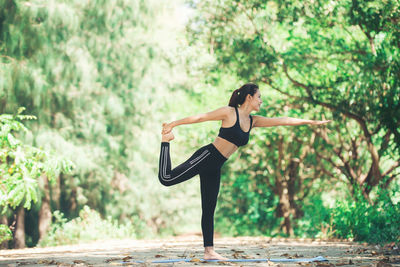 Full length of young woman practicing yoga in warrior position at park