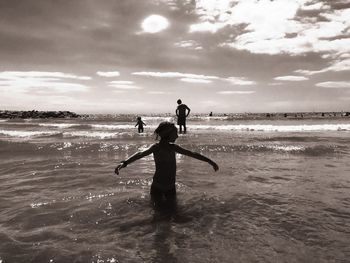 Silhouette with family in background enjoying at beach