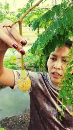 Close-up of girl holding tree trunk