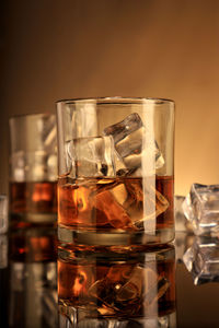 Close-up of whiskey in glass with ice cubes on table