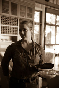 Young woman with plates and bowl standing in winery