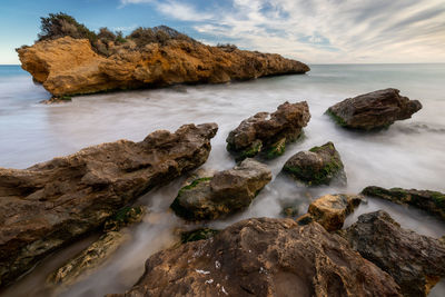 Rocks in sea against sky
