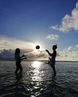 Man playing with ball in sea against sky