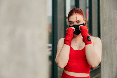 Full length of woman standing against red wall