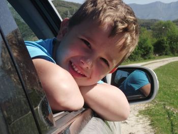 Close-up portrait of cheerful boy in car