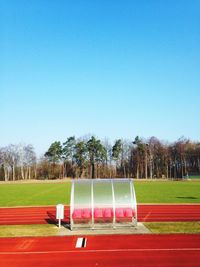 Trees on field against clear blue sky