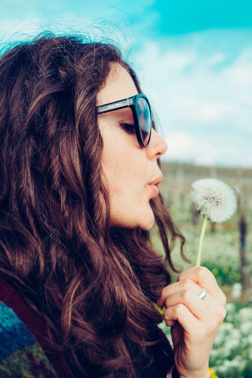 young adult, person, headshot, lifestyles, young women, long hair, leisure activity, focus on foreground, holding, front view, close-up, portrait, sunglasses, looking at camera, human face, head and shoulders