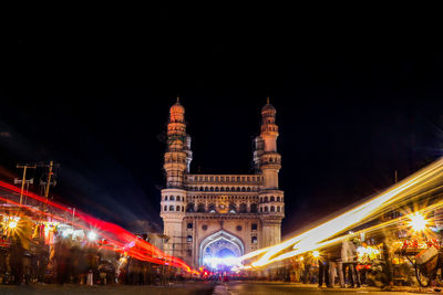 Light trails on road against char minar in illuminated city at night