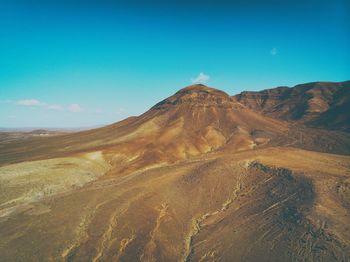 Scenic view of arid landscape against blue sky