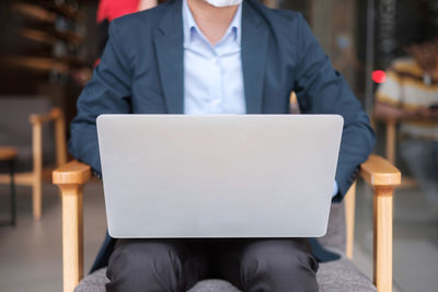 Midsection of man using mobile phone while sitting on seat