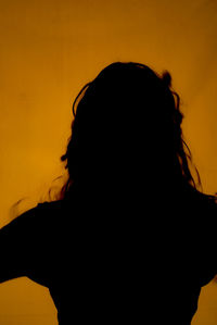 Rear view of silhouette woman against orange sky