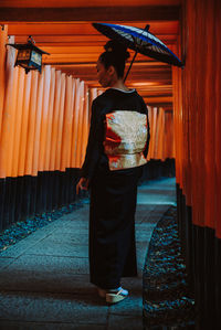 Rear view of woman standing at temple against building