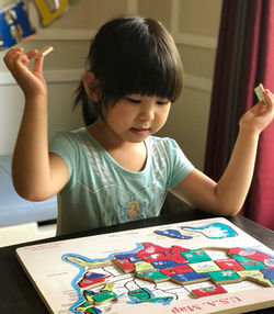 Cute girl holding puzzle pieces at home