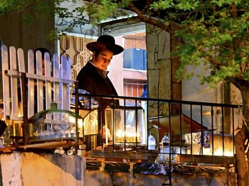 Side view of young man sitting in front of house