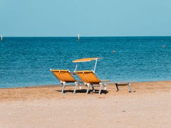 Chairs on beach against clear sky