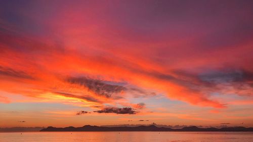 Scenic view of sea against dramatic sky during sunset