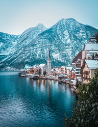 Scenic view of buildings by mountains against sky during winter