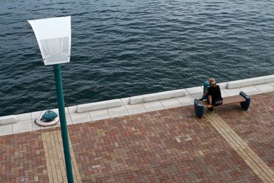 Rear view of man sitting on bench at pier