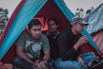 Portrait of friends sitting on tent