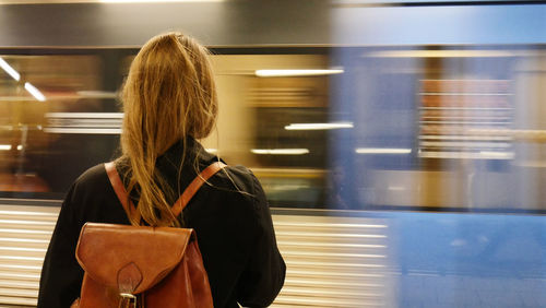 Rear view of woman standing at railroad station