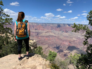 Rear view of woman standing on rock against mountain