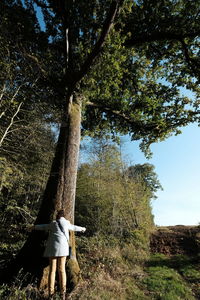 Woman standing by tree on field against sky