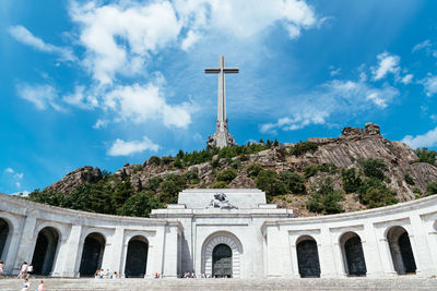 Low angle view of historical building and cross against blue sky