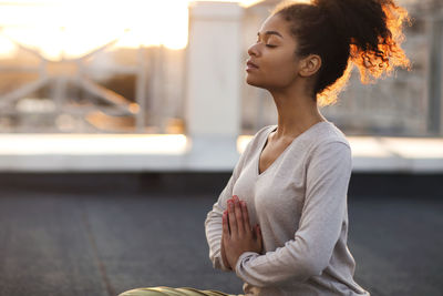Young woman looking away while sitting on table