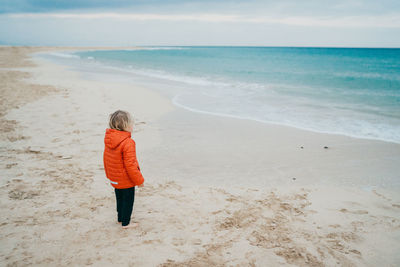 Kid boy wearing a jacket at the beach on a cold day