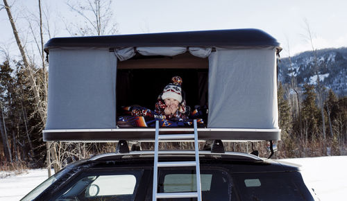 Portrait of smiling boy sitting in roof tent on car