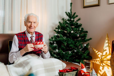 Portrait of smiling family playing with christmas tree at home