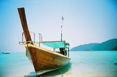 Boat moored in calm sea against clear sky