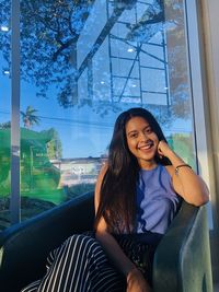 Portrait of smiling woman sitting by window