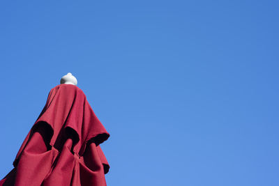 Low angle view of red hanging against blue sky