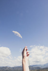 Low section of person holding hands against blue sky