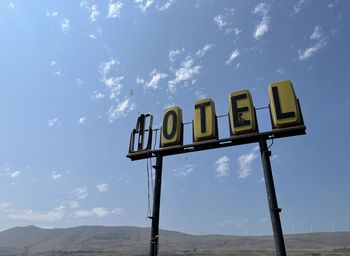 Low angle view of a run down motel sign against sky