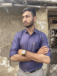 Portrait of young man standing against wall