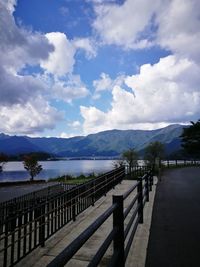 View of calm lake in front of mountains against cloudy sky