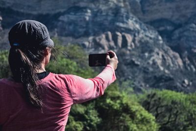 Rear view of young woman photographing through mobile phone