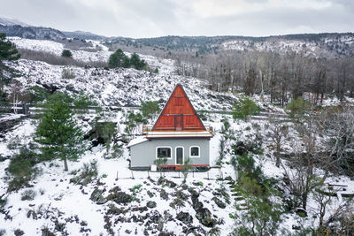 House on snow covered mountain against sky