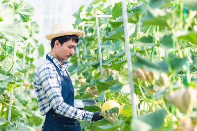 Portrait of young man standing amidst plants