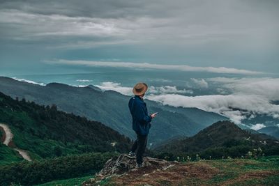 Side view of man standing on mountain against sky