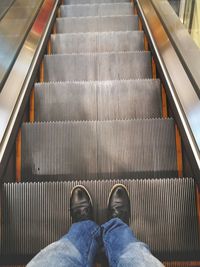 Low section of person standing on escalator