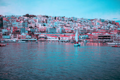 Sailboats in sea against buildings in city