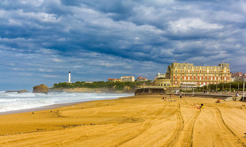 View of beach and buildings against cloudy sky