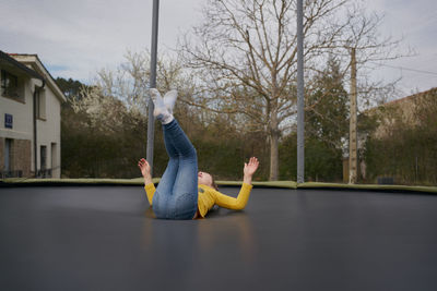 A girl in casual clothes jumping on a trampoline