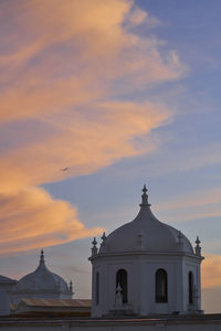 Lighthouse by sea against sky during sunset